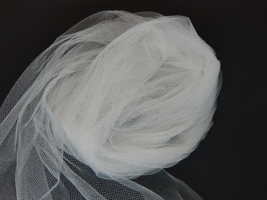 A pile of white tulle in a kind of spiral shape on a black background