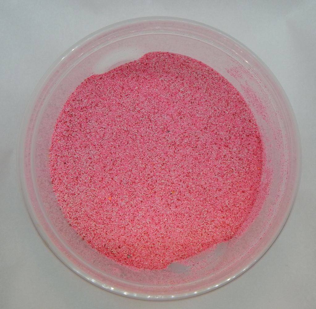 a translucent plastic bowl holding dark pink granular sand
